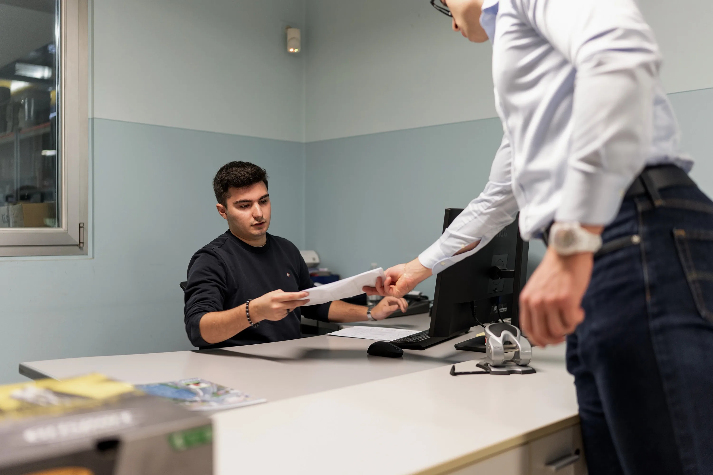 Due colleghi si scambiano documenti in un ufficio moderno