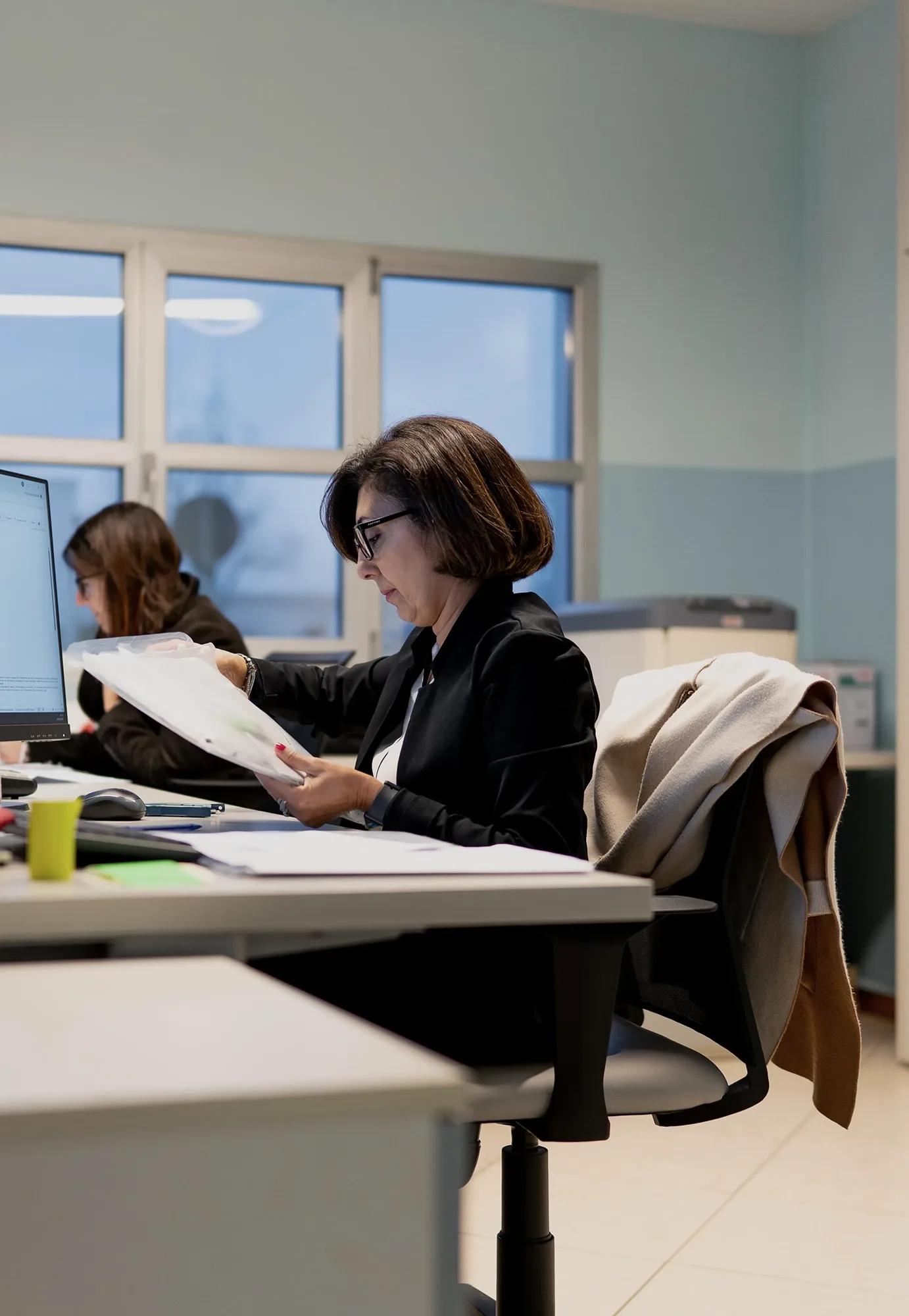 Impiegate al lavoro in ufficio mentre consultano dei documenti