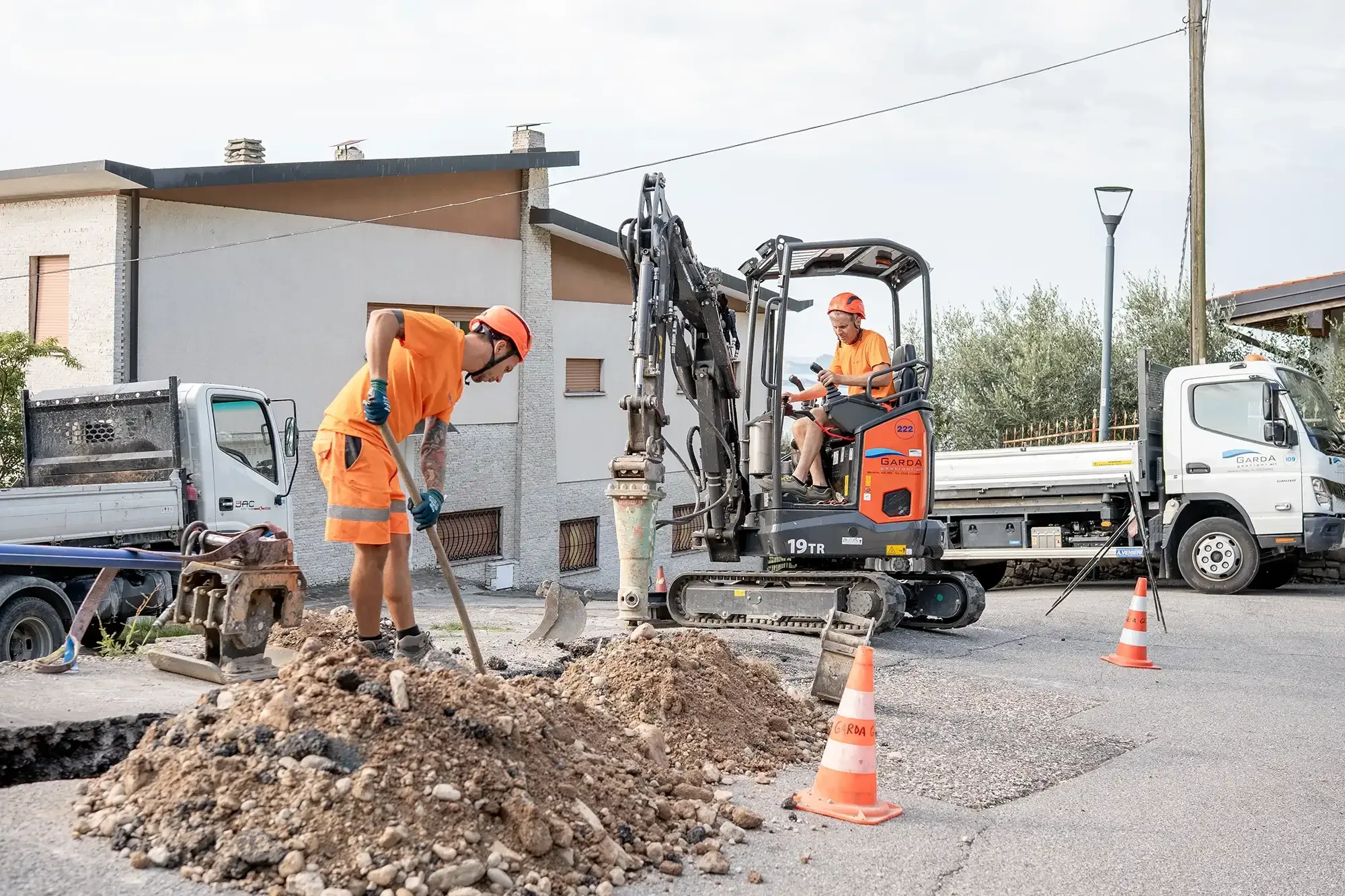 Operai eseguono lavori stradali con escavatore a Manerba del Garda