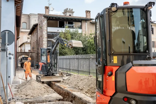 Lavori stradali con mini escavatore e operai a Manerba del Garda