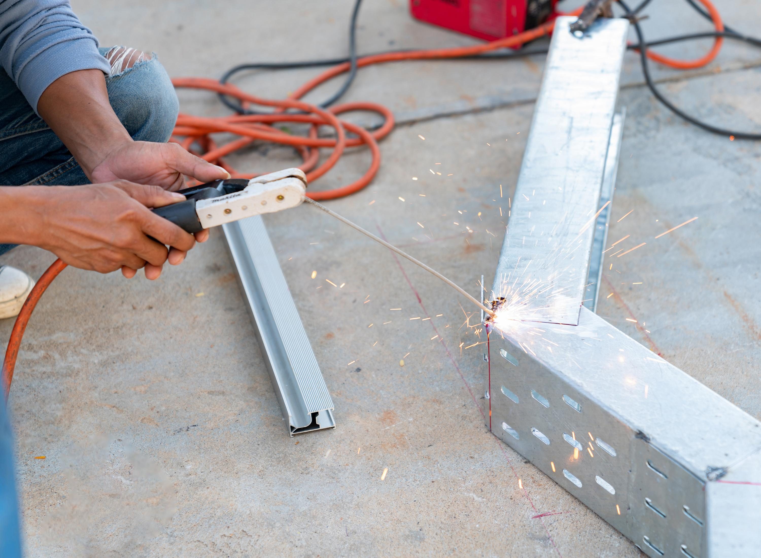 Operaio che salda una struttura metallica su un pavimento in cemento
