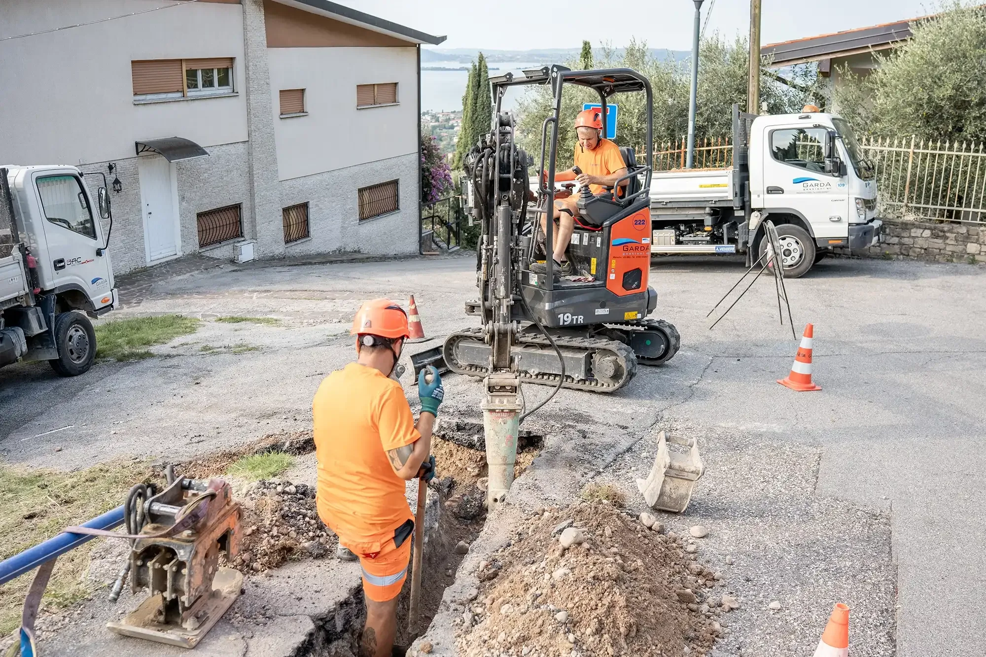 Operai effettuano lavori stradali con mini escavatore a Manerba del Garda