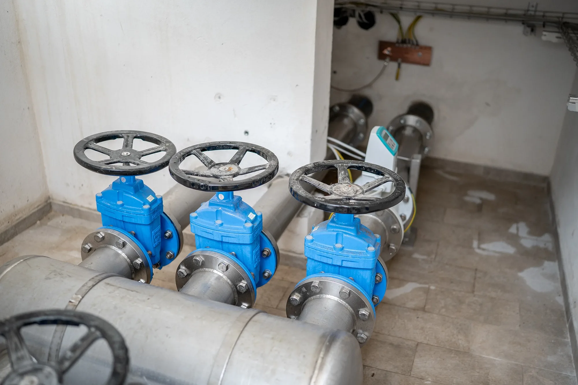 Valvole industriali blu collegate a tubature in un impianto idrico